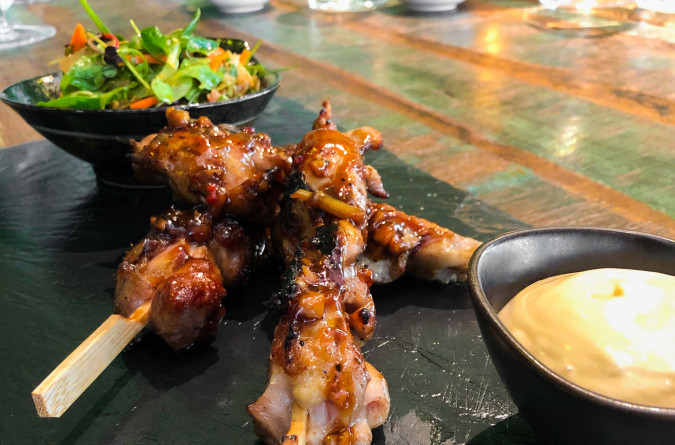 Meat skewers with dip and lettuce on a slate board